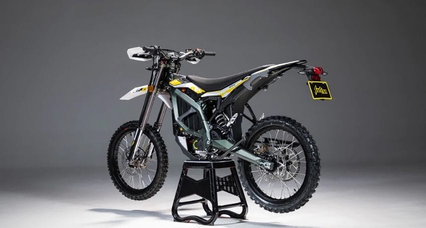 A dirt bike sits on a stand in front of a gray background.