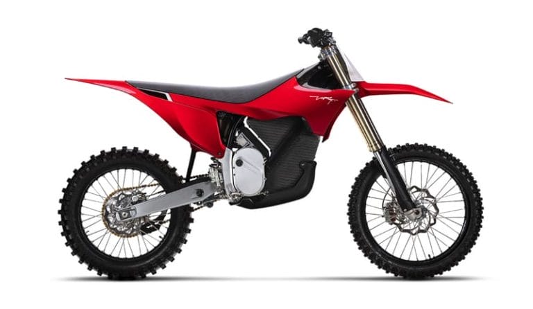 Side view of a red and black dirt bike with knobbed tires, an elongated seat, and a high front fender.