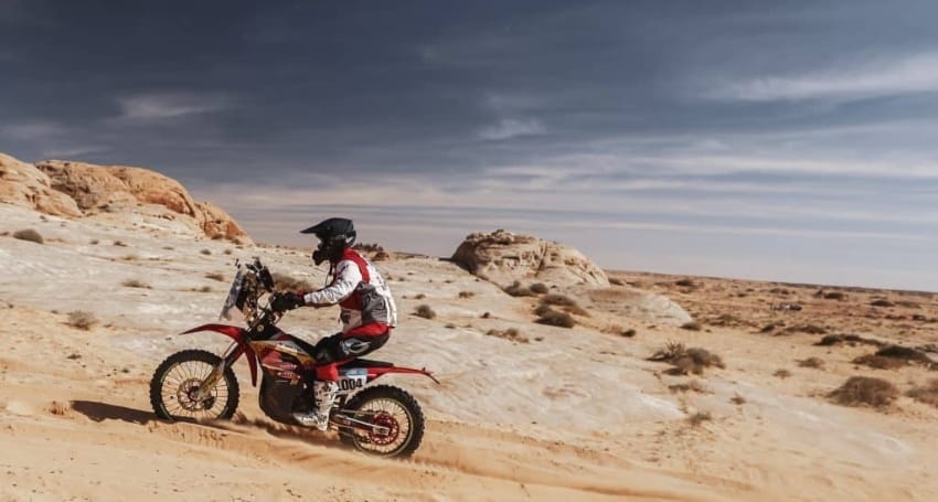 Motorcyclist riding through a desert landscape.