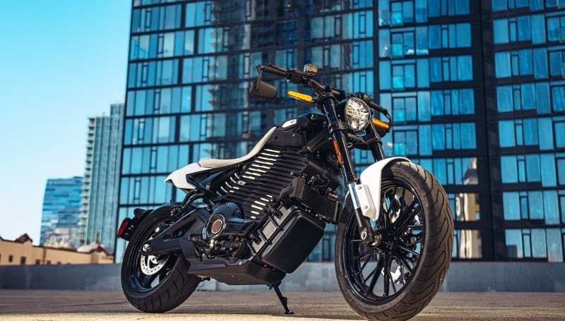 A modern motorcycle parked in front of a glass facade building under a clear sky.