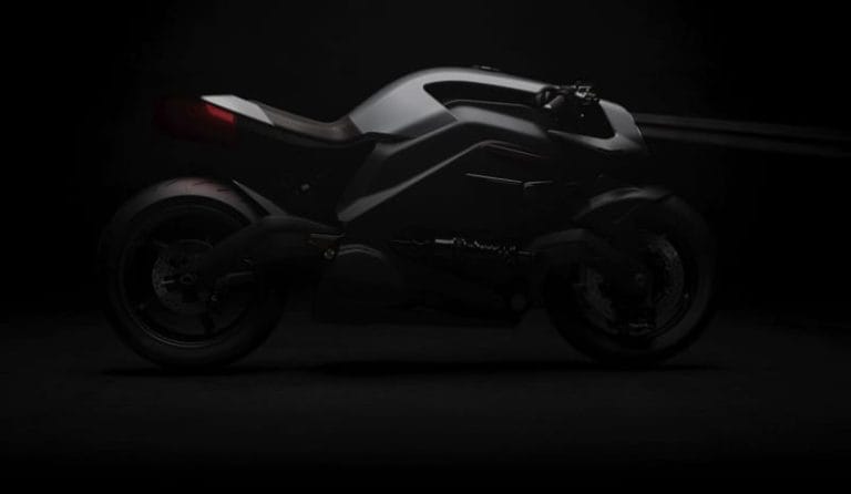 A black motorcycle with a sleek, futuristic design is shown in a dark setting, highlighting its contours and details.