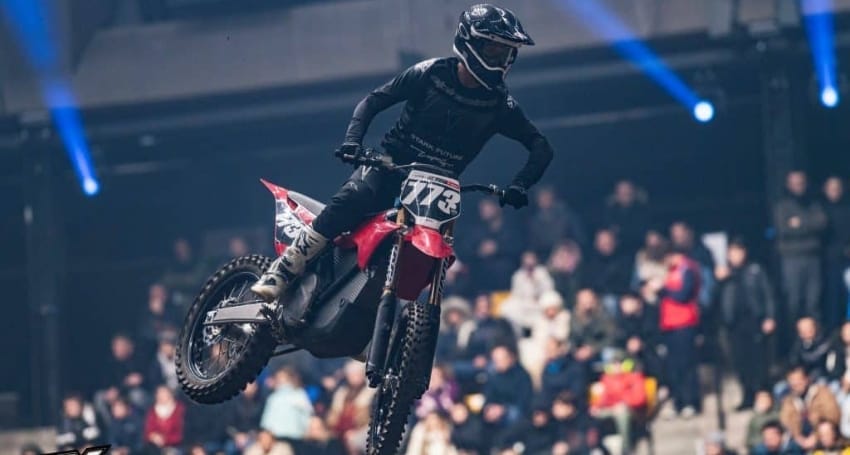 Motocross rider performing a jump at an indoor arena event.