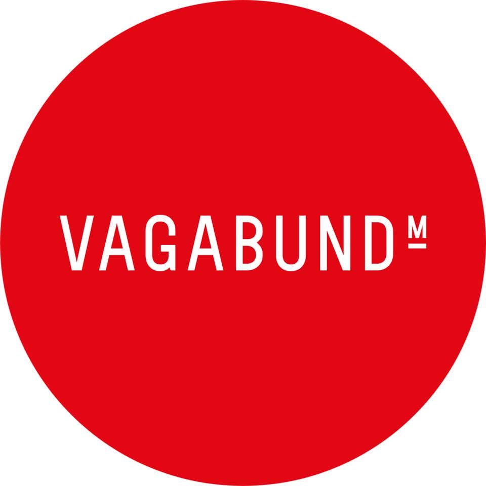 A red circle with the word "VAGABUND" in white, capital letters, positioned in the center. A small "M" is located at the top right of the word.