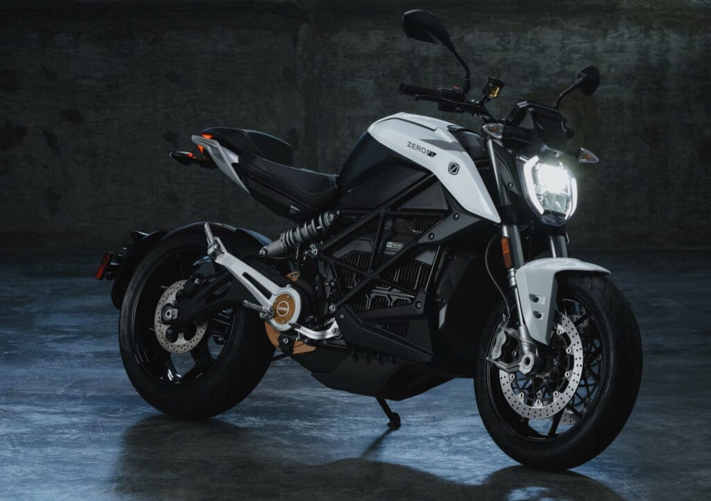 A black and white motorcycle parked in a dark room.