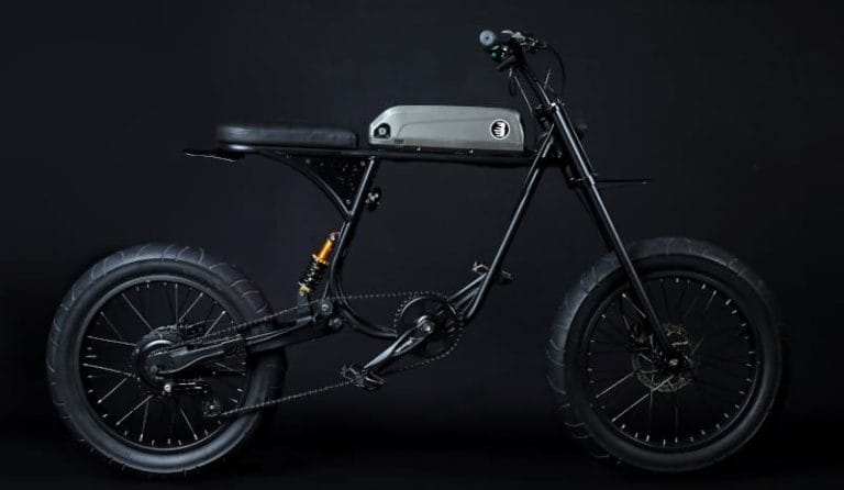 A black e-bike with a minimalist design, featuring thick tires, a padded seat, and rear suspension, set against a dark background.