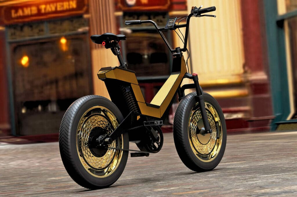 A gold and black electric bike is parked on a cobblestone street.