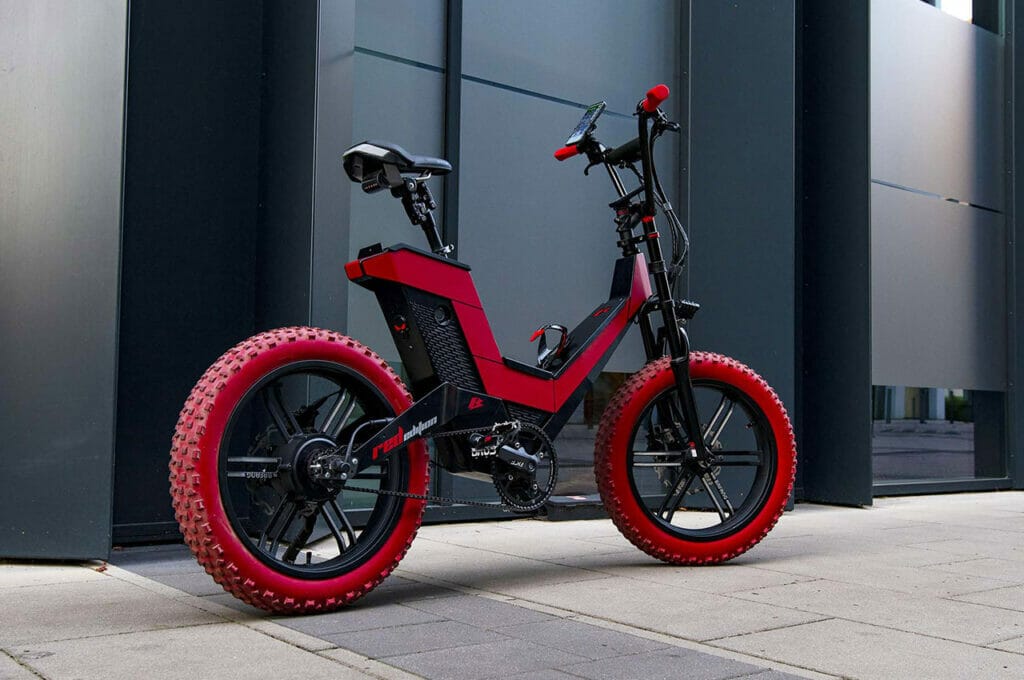 A red and black electric bike parked in front of a building.