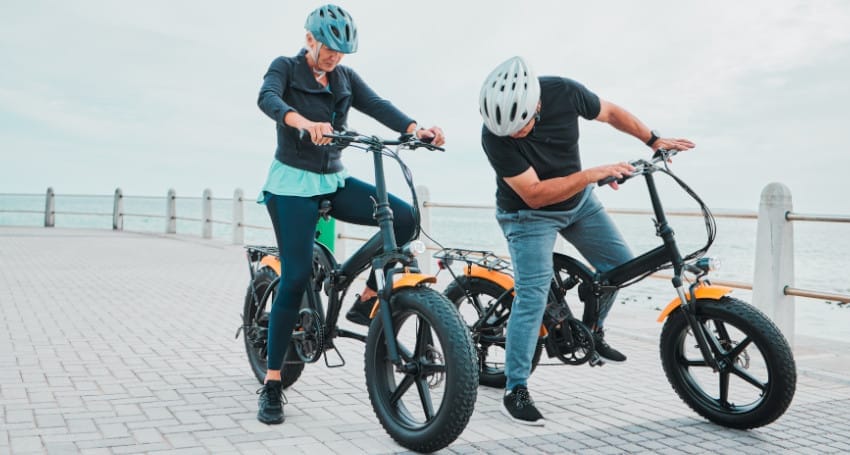 A couple enjoying an electric bike ride on the beach.