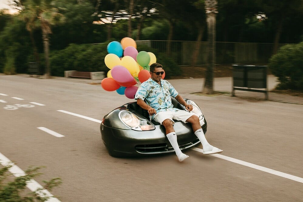 A man sitting in a car with balloons on it.