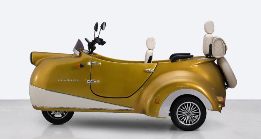 A gold and cream three-wheeled electric vehicle with two seats and a sleek, retro design.