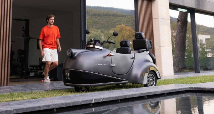 A man is standing in front of a house with a motorized scooter.