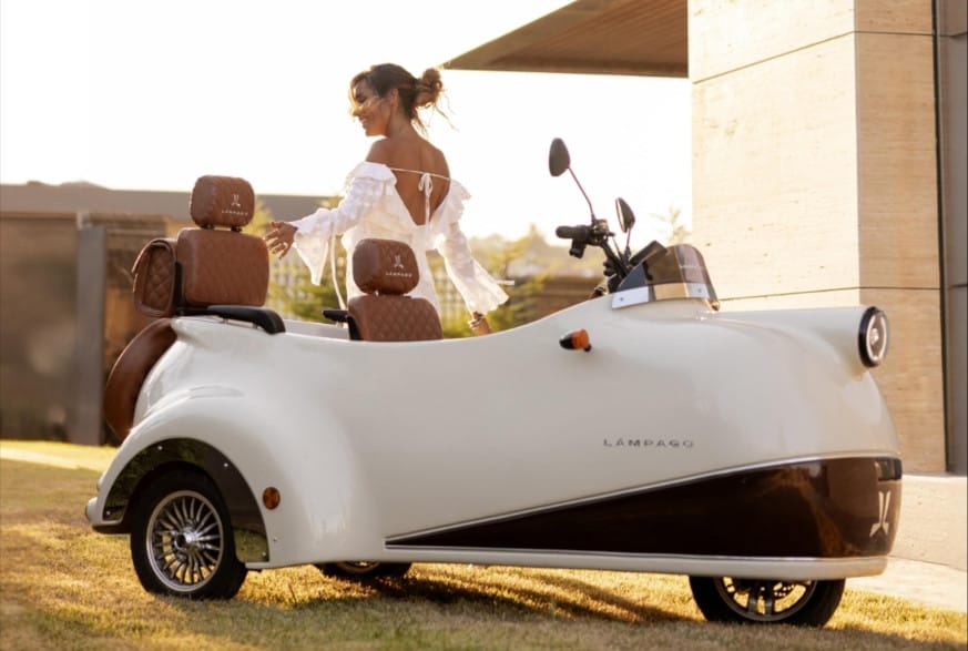 A woman is standing next to a white tricycle in front of a house.