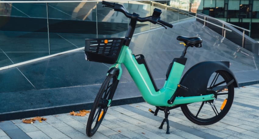 A green e-bike parked in front of a building.