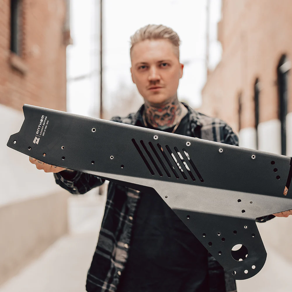 A man with tattoos holding up a metal blade.