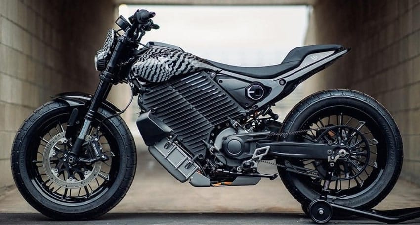 A modern black electric motorcycle with a sleek design, parked inside a concrete tunnel.