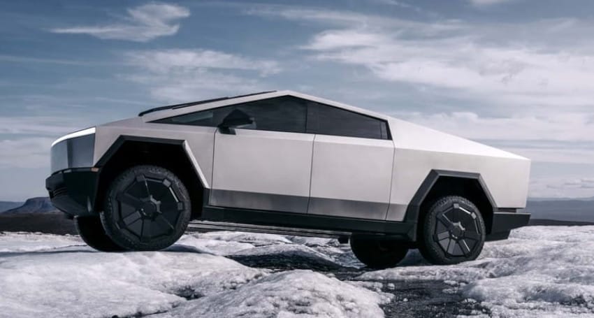 A futuristic, angular, metallic SUV gears up to drive across a snowy landscape under a cloudy sky.