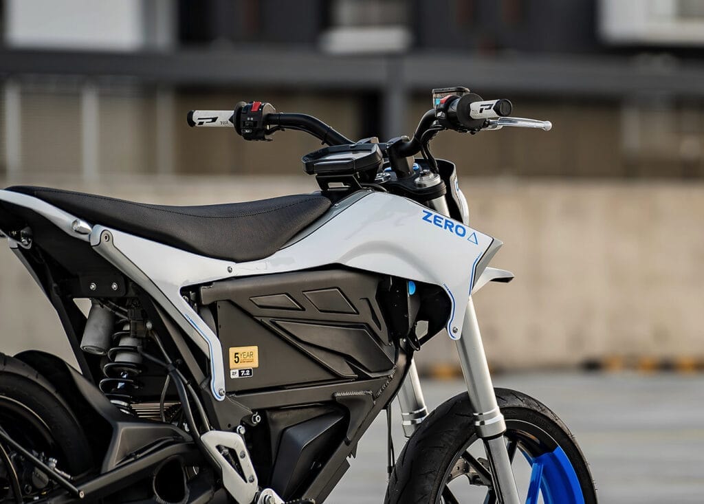 A white and blue electric motorcycle parked in front of a building.