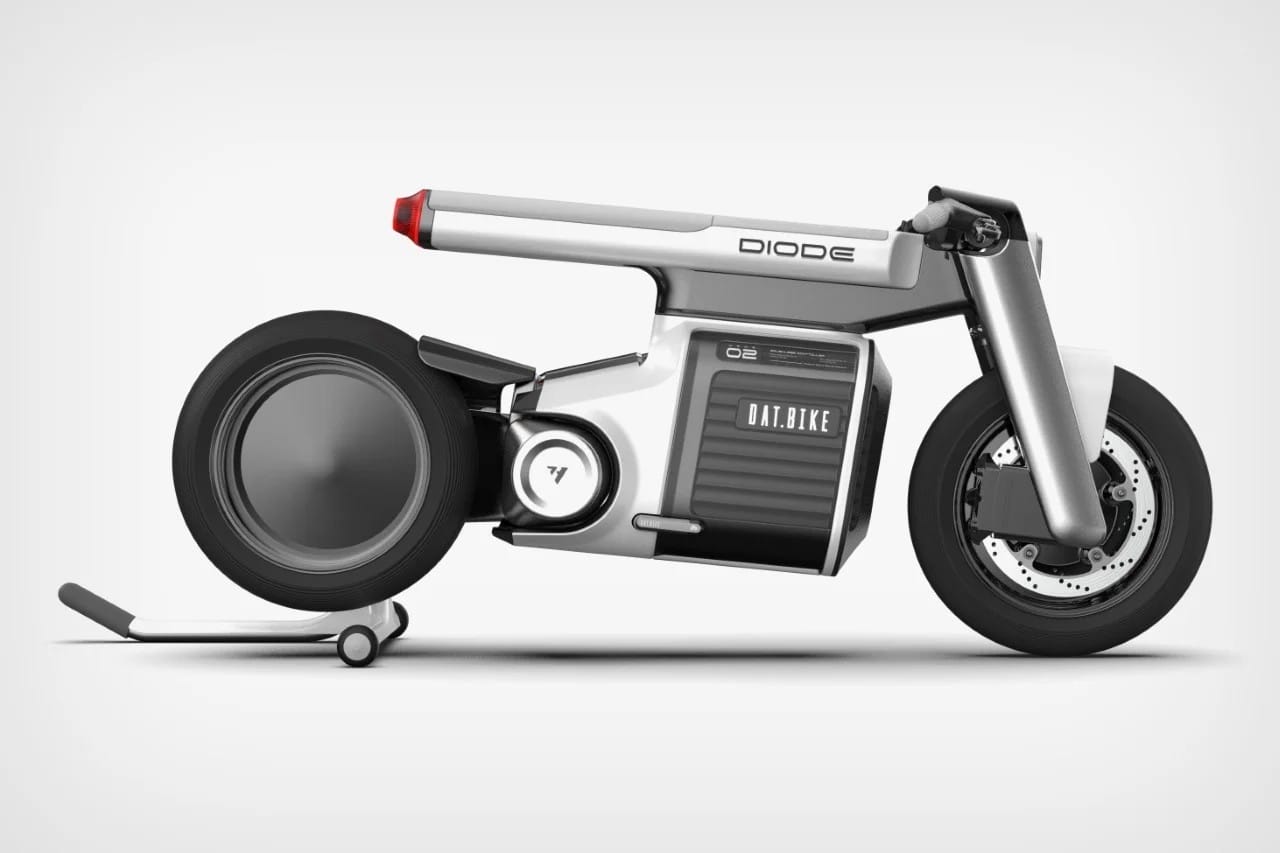 A futuristic, minimalistic electric motorcycle with a sleek, grey design, labeled "Diode" on the side. The motorcycle features a unique, compact frame and large disc-like wheels.