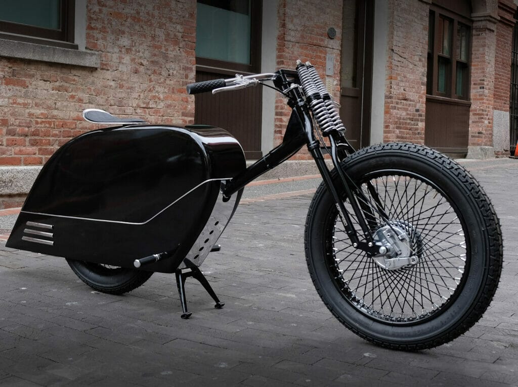 A black motorcycle parked in front of a brick building. (Keywords: black, motorcycle)