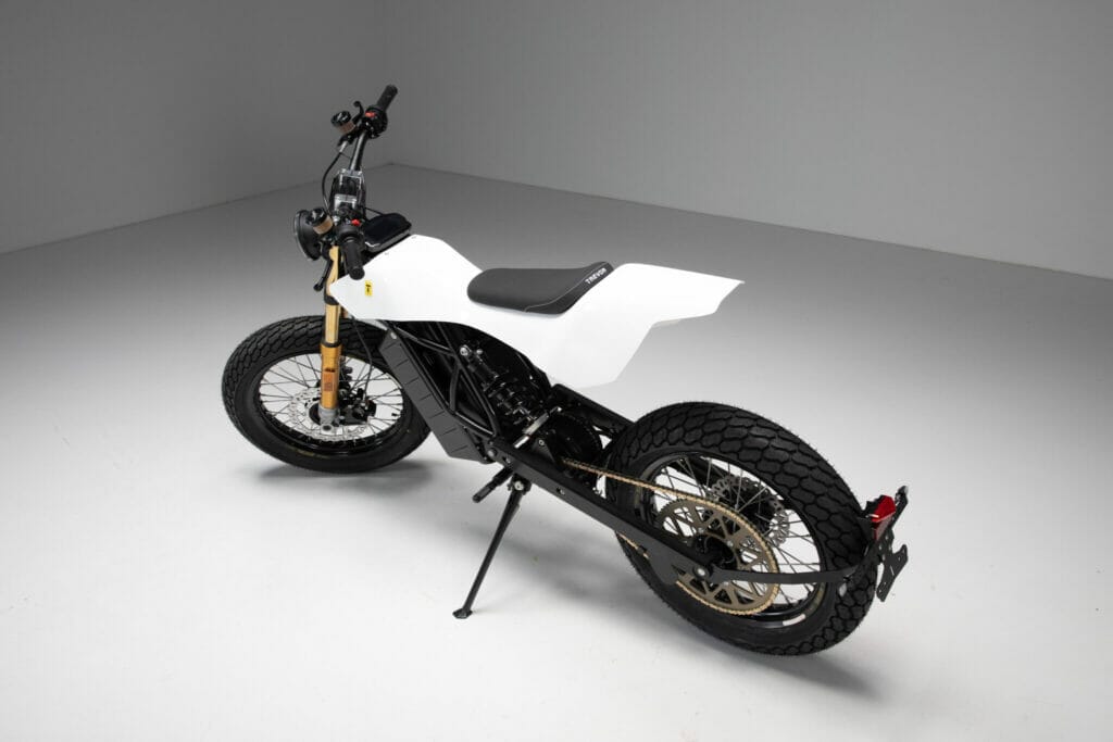 A black and white Trevor electric motorcycle sitting on a white floor at the Revolutionizing Flat Track Racing event featuring the DTRe Stella.