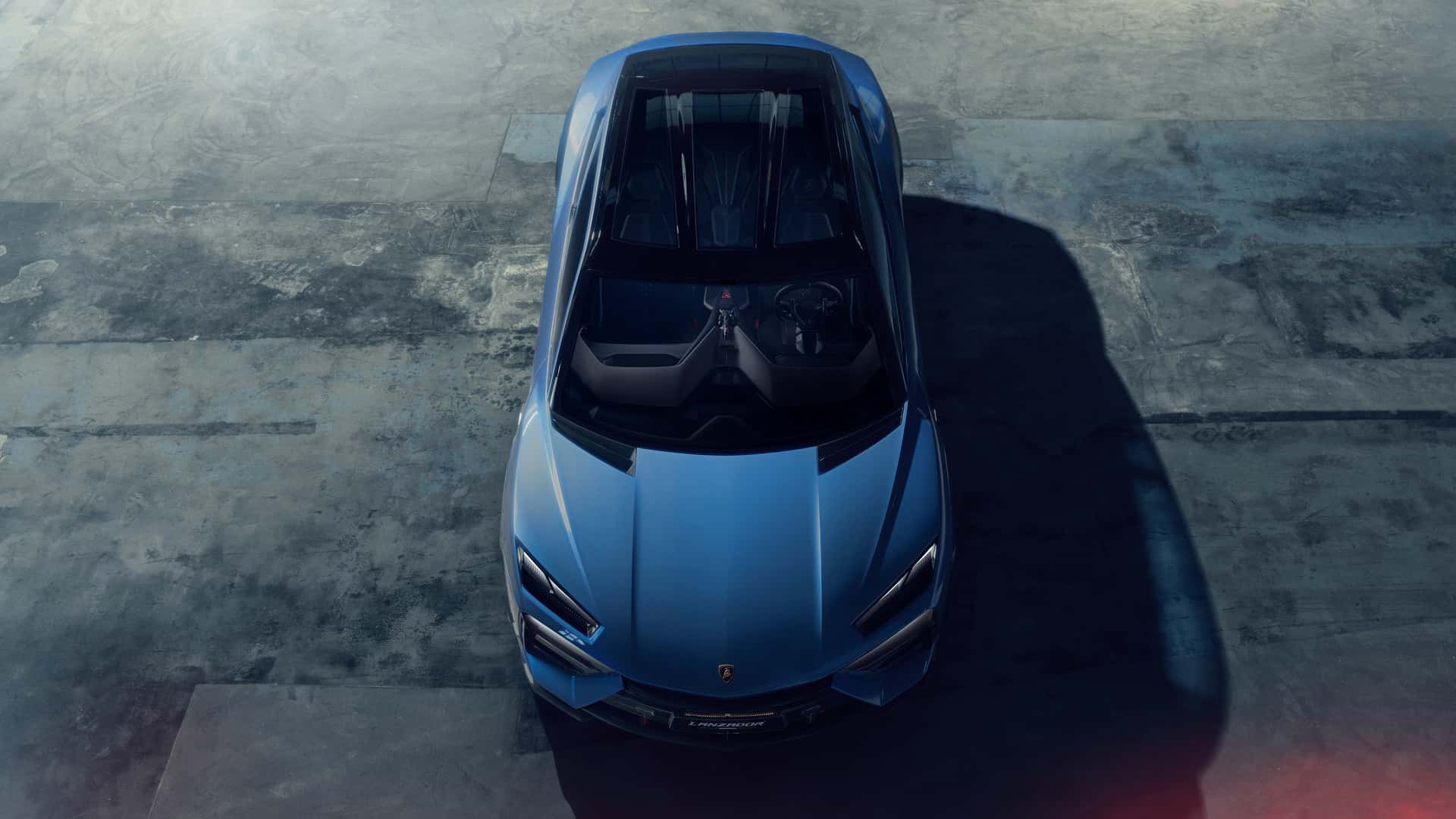 Aerial view of a blue sports car with a sleek, angular design, parked on a concrete surface.